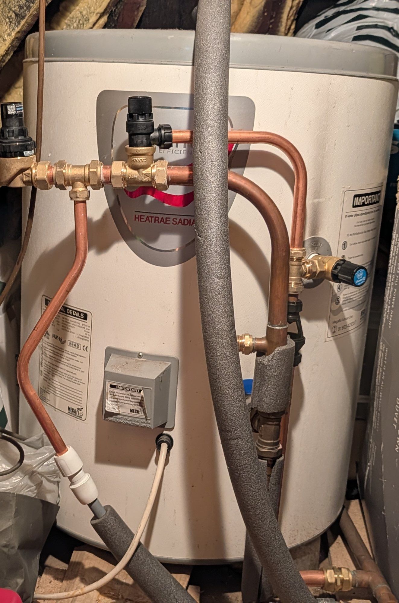 Unvented hot water cylinder and pipework in a loft